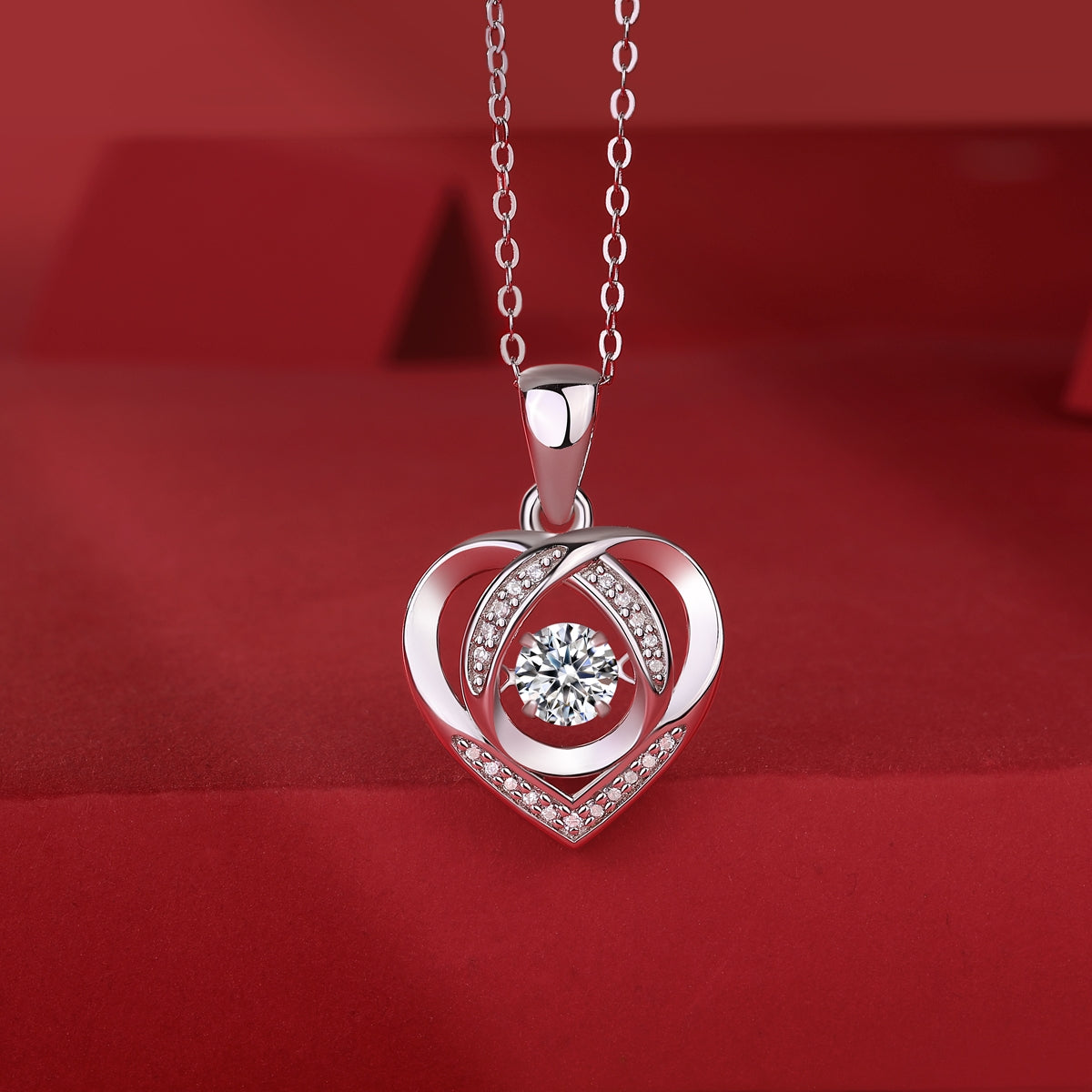 Silver heart-shaped pendant with a diamond on a red background