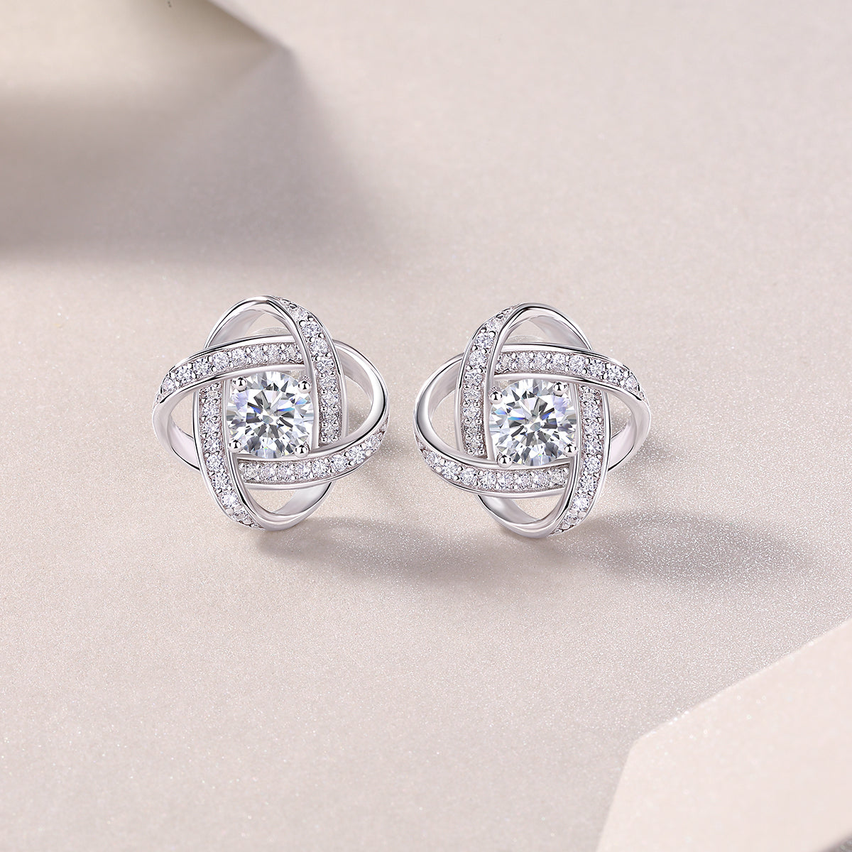 Pair of silver earrings with diamond-like stones on a light background