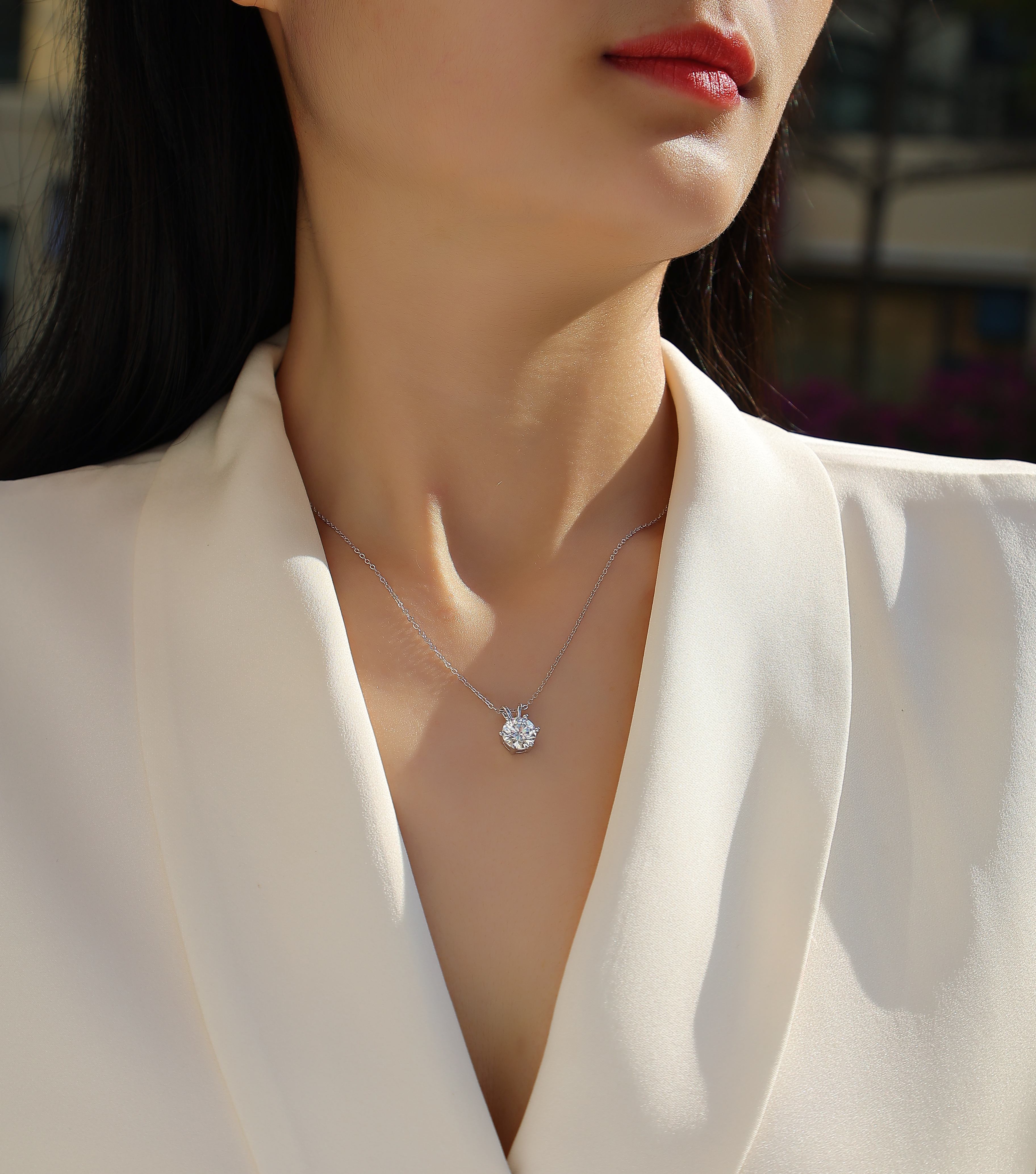 Close-up of a person wearing a diamond necklace against a blurred background