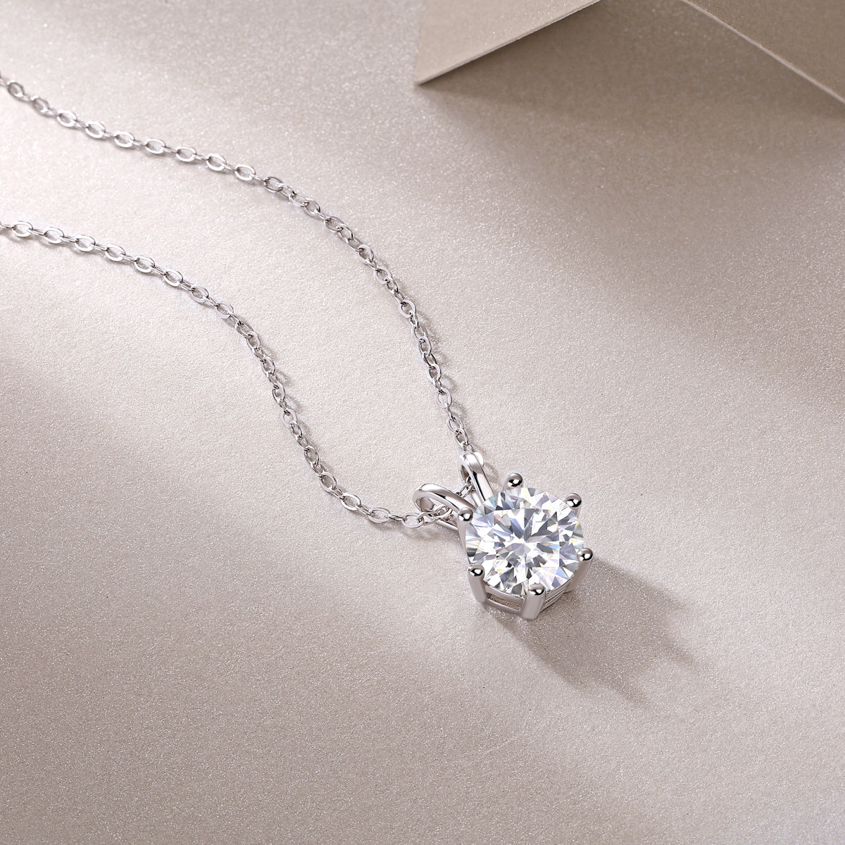 Silver necklace with a diamond pendant on a beige surface