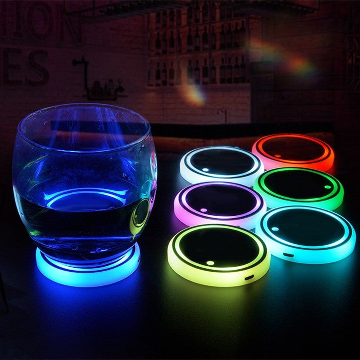 Set of colorful LED coasters with a glass on a dark surface